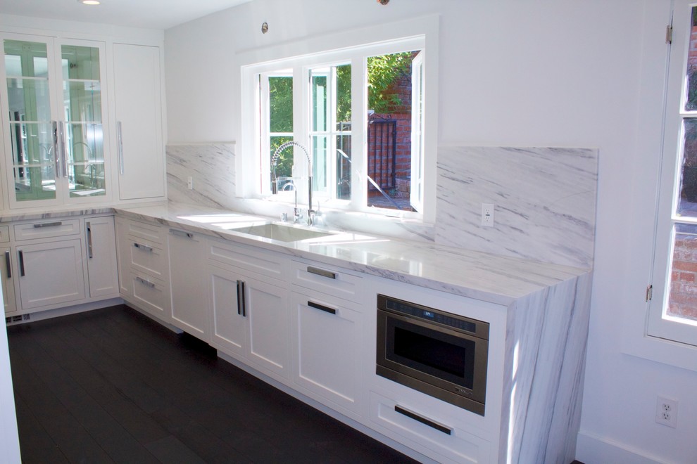 Exempel på ett avskilt modernt u-kök, med en undermonterad diskho, skåp i shakerstil, vita skåp, marmorbänkskiva, grått stänkskydd, stänkskydd i marmor, rostfria vitvaror, mörkt trägolv och svart golv