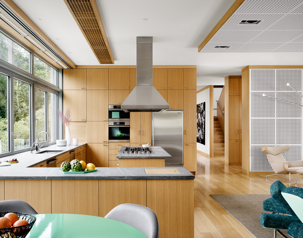 Источник вдохновения для домашнего уюта: большая п-образная кухня-гостиная в современном стиле с врезной мойкой, плоскими фасадами, светлыми деревянными фасадами и техникой из нержавеющей стали