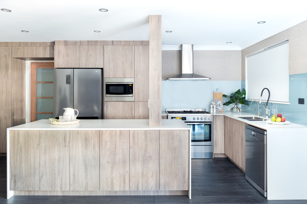 Inspiration for a large contemporary l-shaped kitchen in Perth with a double-bowl sink, glass sheet splashback, stainless steel appliances, an island, grey floors, flat-panel cabinets, beige cabinets, blue splashback and white worktops.