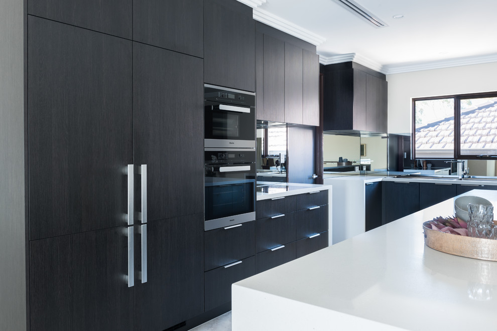 Imagen de cocina minimalista con puertas de armario de madera en tonos medios, salpicadero metalizado, salpicadero con efecto espejo y una isla