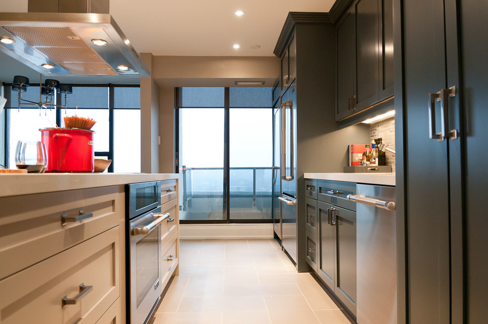 Modern inredning av ett kök, med en undermonterad diskho, skåp i shakerstil, grå skåp, marmorbänkskiva, grått stänkskydd och rostfria vitvaror