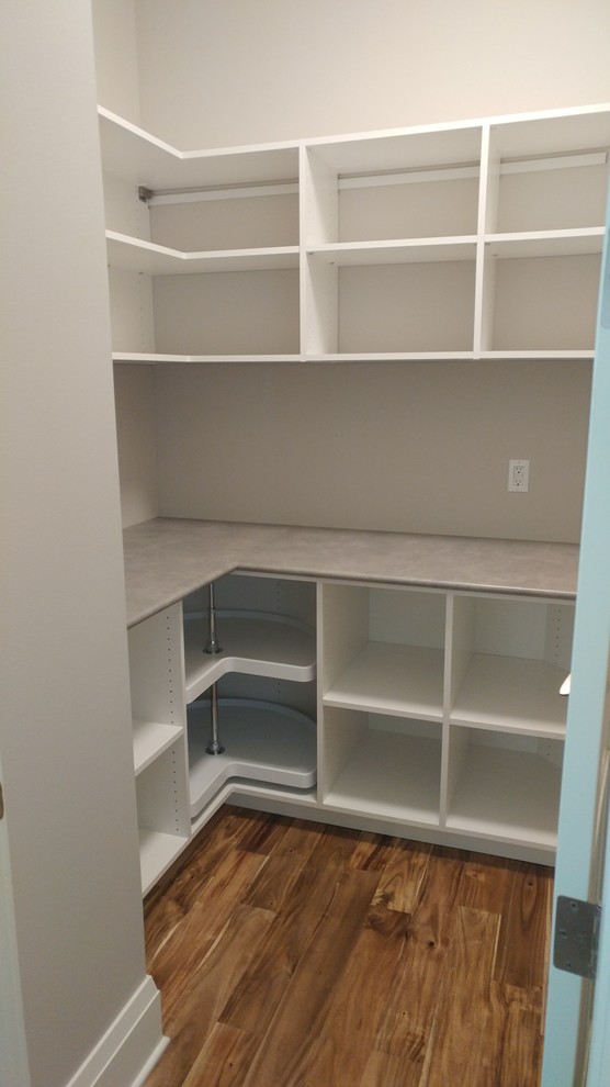 This is an example of a small modern l-shaped kitchen pantry in Milwaukee with open cabinets, white cabinets, medium hardwood flooring, no island and brown floors.