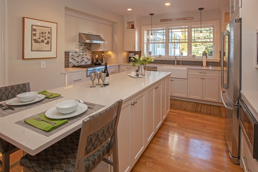 Exempel på ett mellanstort klassiskt kök, med en rustik diskho, luckor med upphöjd panel, vita skåp, bänkskiva i kvarts, grått stänkskydd, stänkskydd i glaskakel, rostfria vitvaror, mellanmörkt trägolv och en köksö