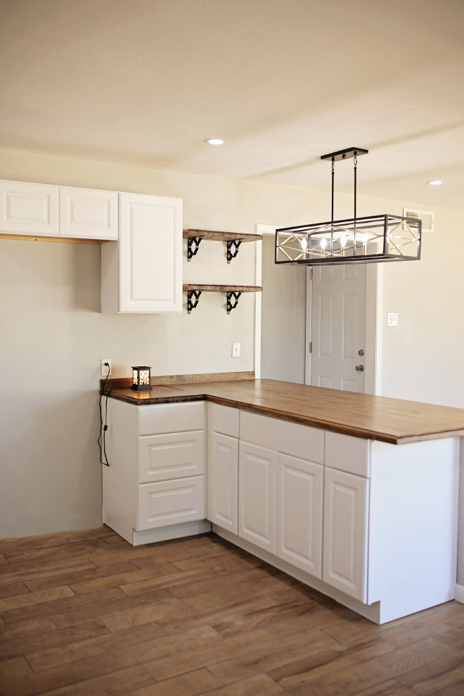 Foto på ett mellanstort brun kök, med en nedsänkt diskho, luckor med upphöjd panel, vita skåp, träbänkskiva, klinkergolv i porslin, en köksö och brunt golv