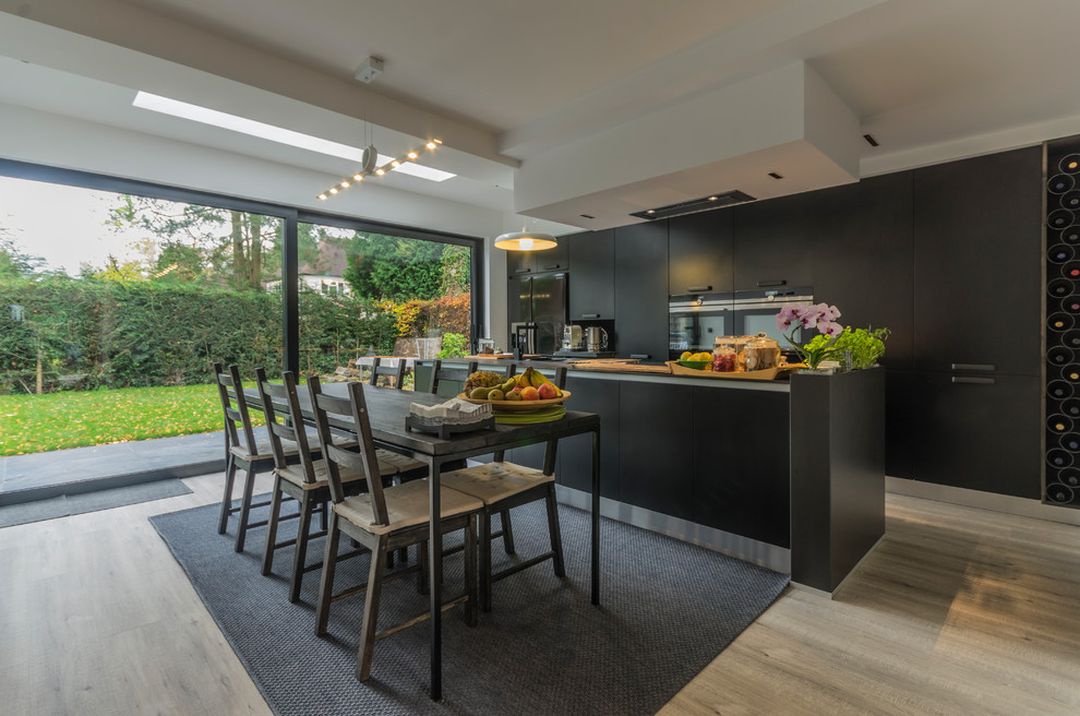 На фото: кухня в стиле модернизм с обеденным столом, плоскими фасадами, черными фасадами и островом с