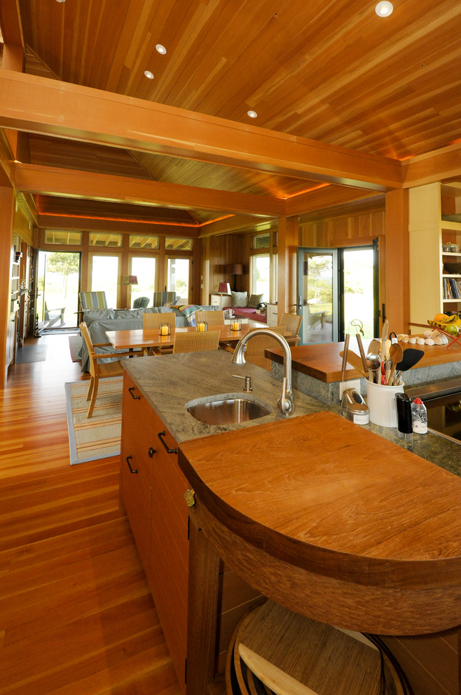 Cette image montre une cuisine marine en bois brun avec un placard à porte plane, un plan de travail en granite, un sol en bois brun et îlot.