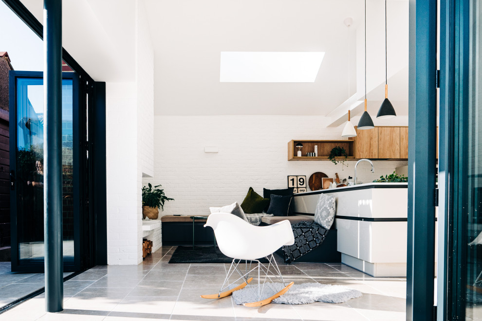 Design ideas for a contemporary l-shaped open plan kitchen in Cardiff with a built-in sink, flat-panel cabinets, beige cabinets, engineered stone countertops, brick splashback, integrated appliances, limestone flooring, no island, beige floors and white worktops.