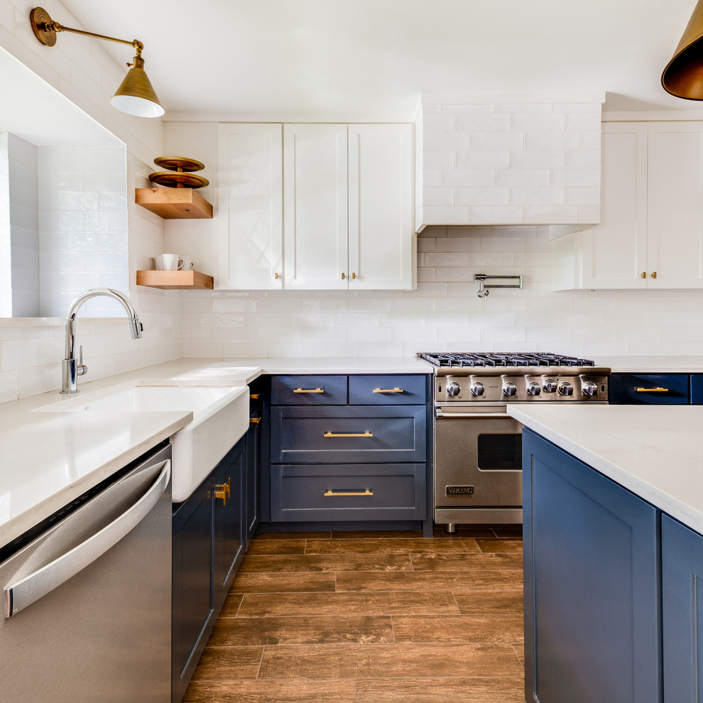 Inspiration for a mid-sized transitional u-shaped medium tone wood floor and brown floor kitchen remodel in Dallas with a farmhouse sink, shaker cabinets, blue cabinets, quartz countertops, white backsplash, ceramic backsplash, stainless steel appliances, an island and white countertops