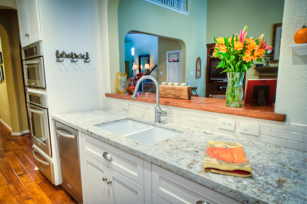Example of a classic eat-in kitchen design in Houston with an undermount sink, shaker cabinets, white cabinets, granite countertops, white backsplash and stainless steel appliances