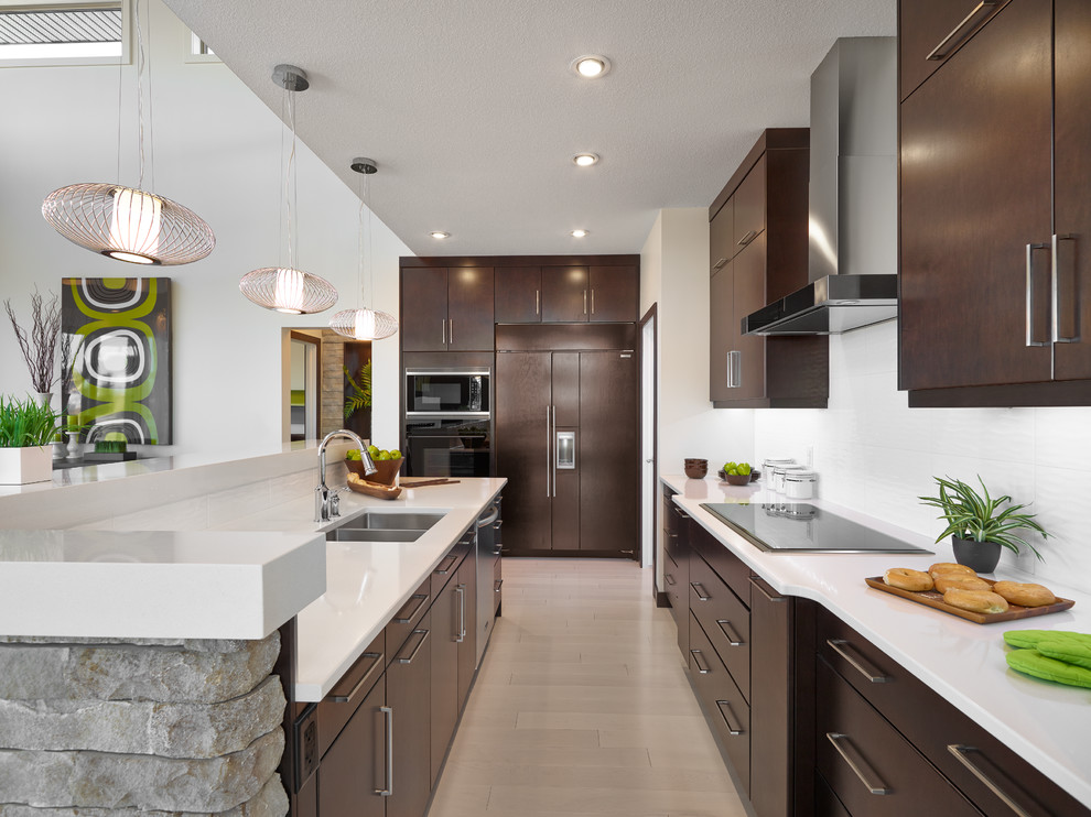 Design ideas for a contemporary galley kitchen in Calgary with a double-bowl sink, flat-panel cabinets, dark wood cabinets, white splashback, stainless steel appliances, light hardwood flooring and an island.