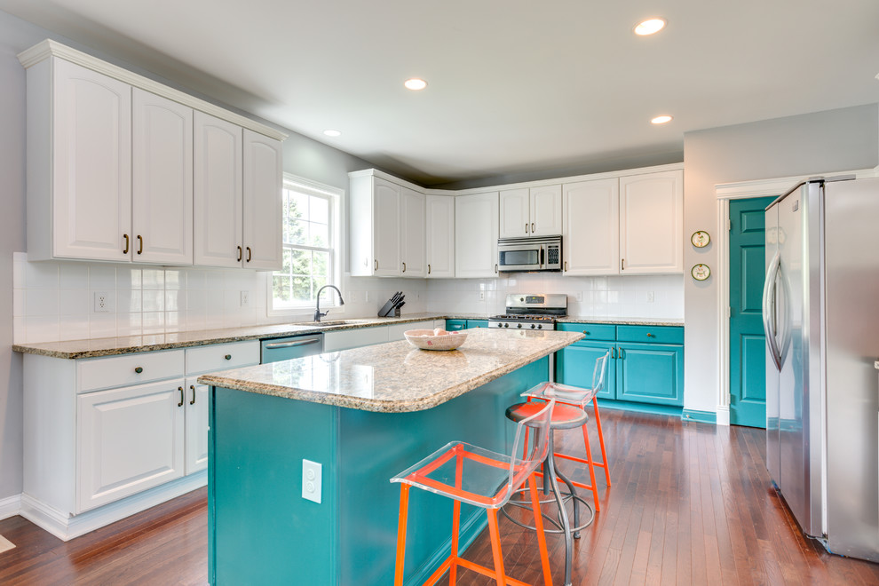 Example of a large trendy galley medium tone wood floor eat-in kitchen design in Columbus with a single-bowl sink, raised-panel cabinets, white cabinets, granite countertops, white backsplash, ceramic backsplash, stainless steel appliances and an island