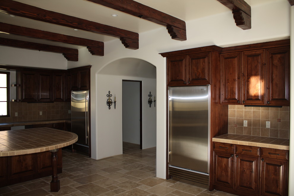 Large tuscan travertine floor kitchen photo in Phoenix with an undermount sink, raised-panel cabinets, medium tone wood cabinets, tile countertops, cement tile backsplash, stainless steel appliances and two islands