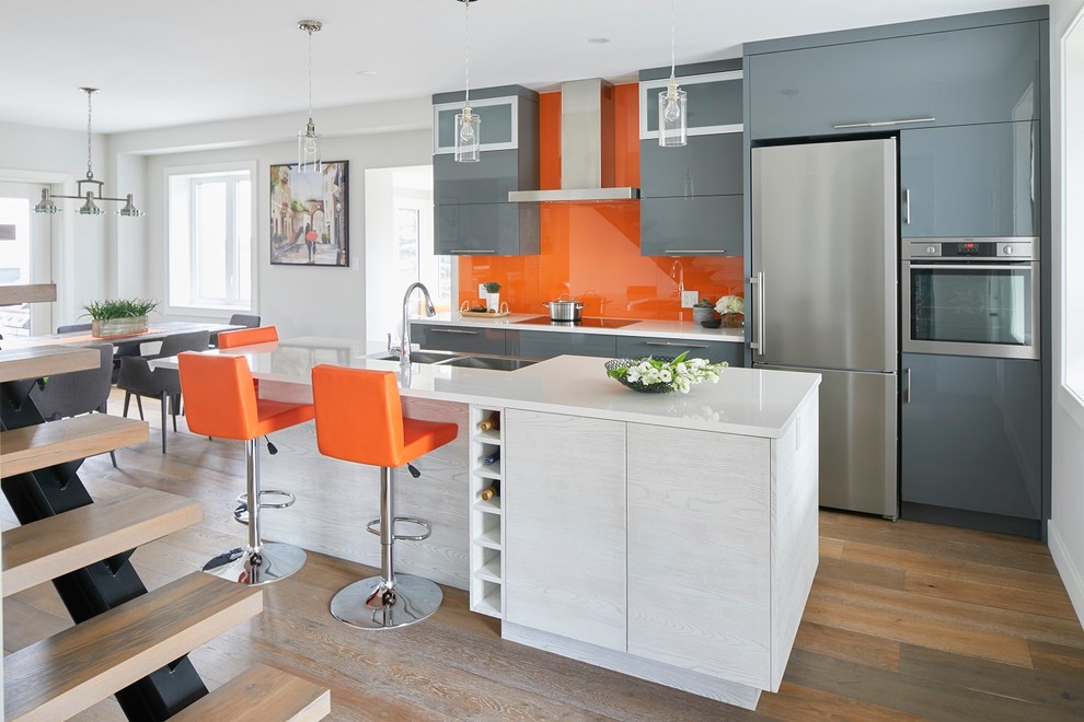 Einzeilige, Mittelgroße Moderne Wohnküche mit Landhausspüle, flächenbündigen Schrankfronten, grauen Schränken, Küchenrückwand in Orange, Rückwand aus Glasfliesen, Küchengeräten aus Edelstahl, dunklem Holzboden, Kücheninsel und braunem Boden in Toronto