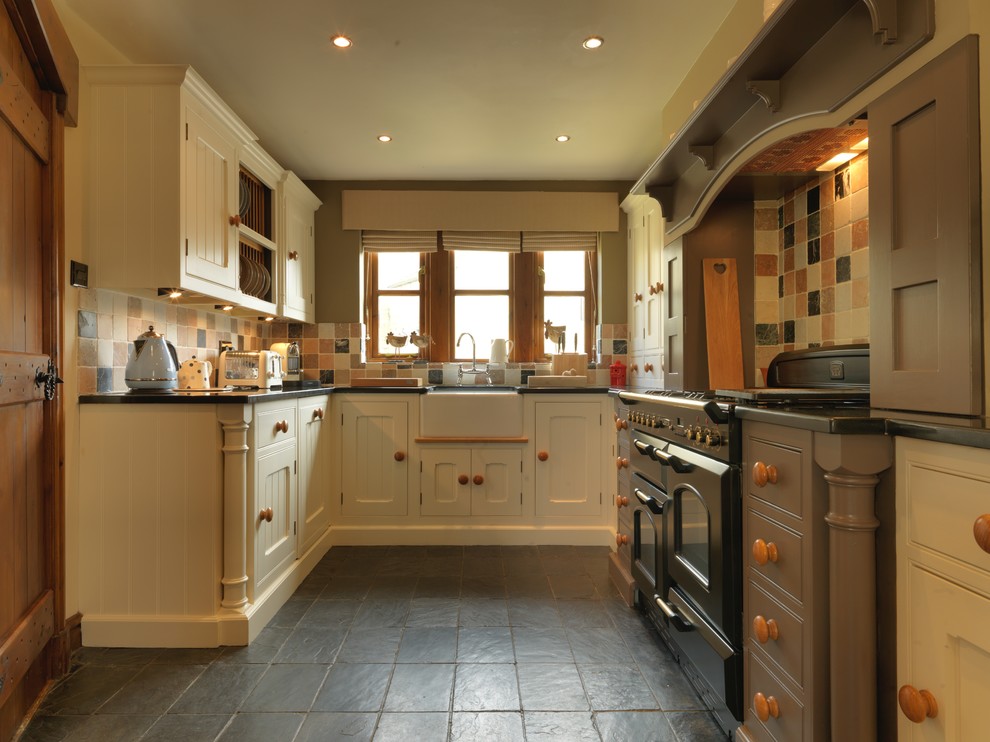 Photo of a country galley kitchen in Other with a belfast sink, shaker cabinets, granite worktops, black appliances and slate flooring.