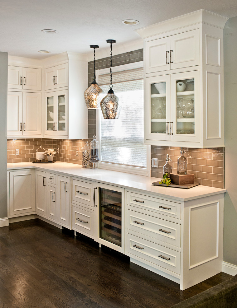 Klassisk inredning av ett mycket stort vit vitt kök med öppen planlösning, med luckor med profilerade fronter, gula skåp, bänkskiva i kvartsit, brunt stänkskydd, en köksö, integrerade vitvaror och brunt golv