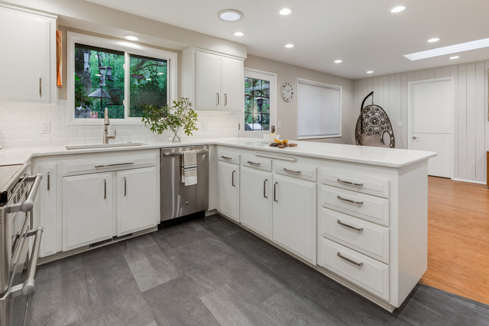 Bild på ett litet vintage vit vitt kök, med en undermonterad diskho, vita skåp, bänkskiva i kvartsit, vitt stänkskydd, stänkskydd i tunnelbanekakel, rostfria vitvaror, skiffergolv och grått golv