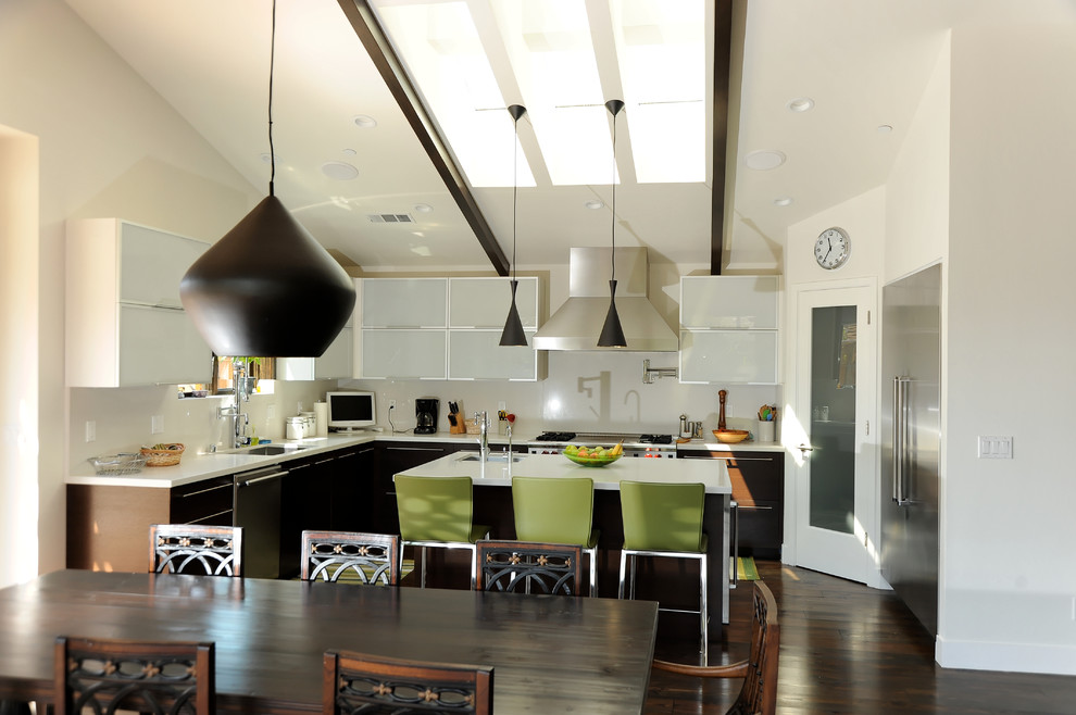 Eat-in kitchen - large modern l-shaped dark wood floor eat-in kitchen idea in San Francisco with a farmhouse sink, glass-front cabinets, dark wood cabinets, solid surface countertops, white backsplash, stone slab backsplash, stainless steel appliances and an island