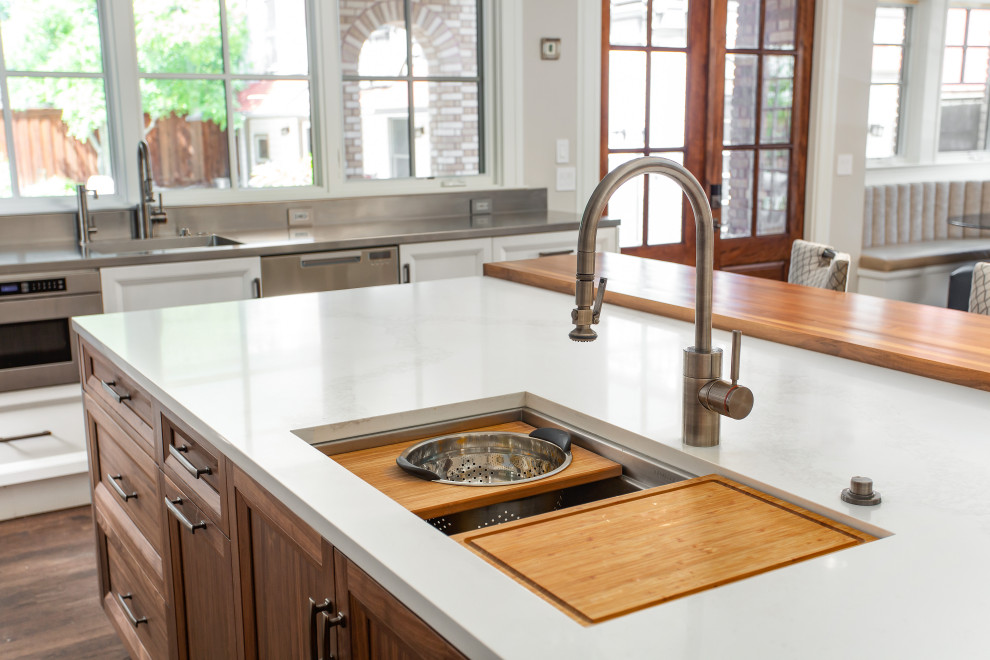 Exempel på ett stort amerikanskt grå grått kök, med en undermonterad diskho, luckor med infälld panel, vita skåp, bänkskiva i rostfritt stål, flerfärgad stänkskydd, stänkskydd i marmor, rostfria vitvaror, mörkt trägolv, en köksö och brunt golv