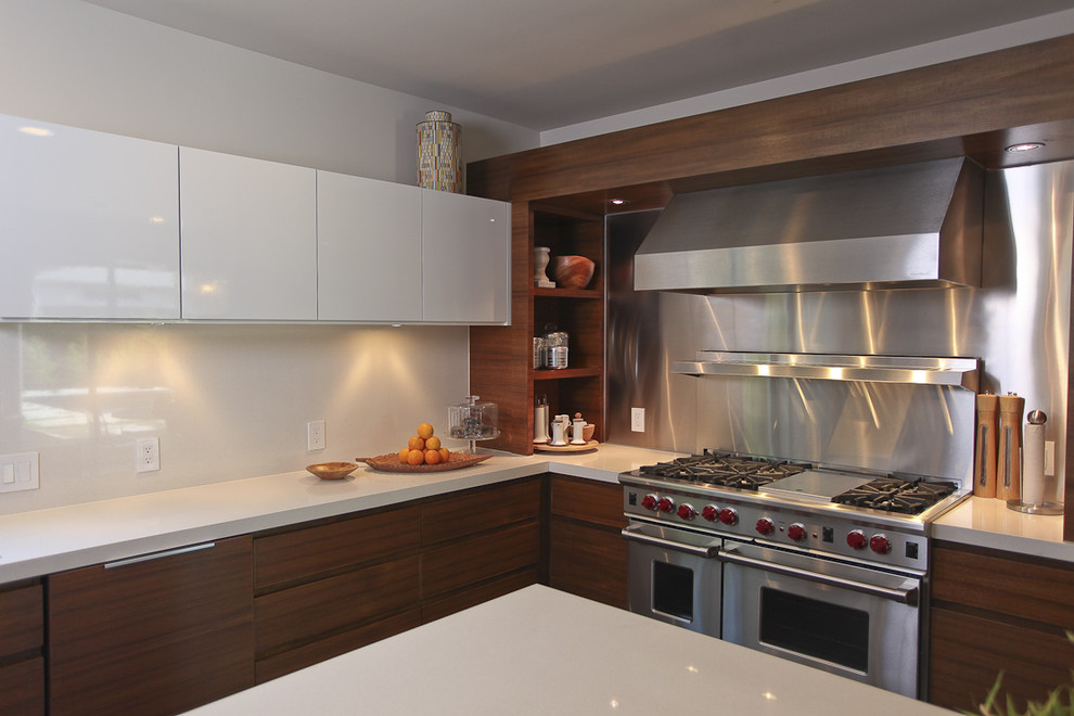 Esempio di una cucina minimal con elettrodomestici in acciaio inossidabile, ante lisce, ante in legno bruno, paraspruzzi a effetto metallico e paraspruzzi con piastrelle di metallo