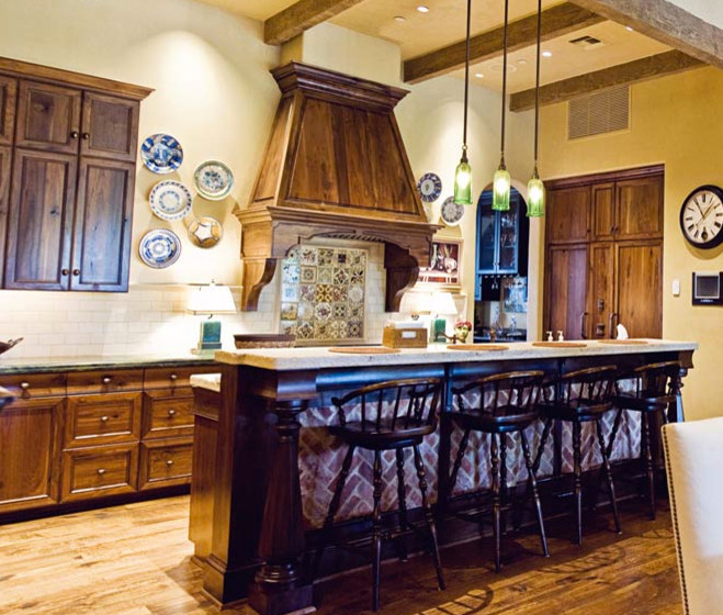Mid-sized galley medium tone wood floor and brown floor eat-in kitchen photo in Dallas with recessed-panel cabinets, medium tone wood cabinets, solid surface countertops, white backsplash, ceramic backsplash, paneled appliances, an island, an undermount sink and beige countertops