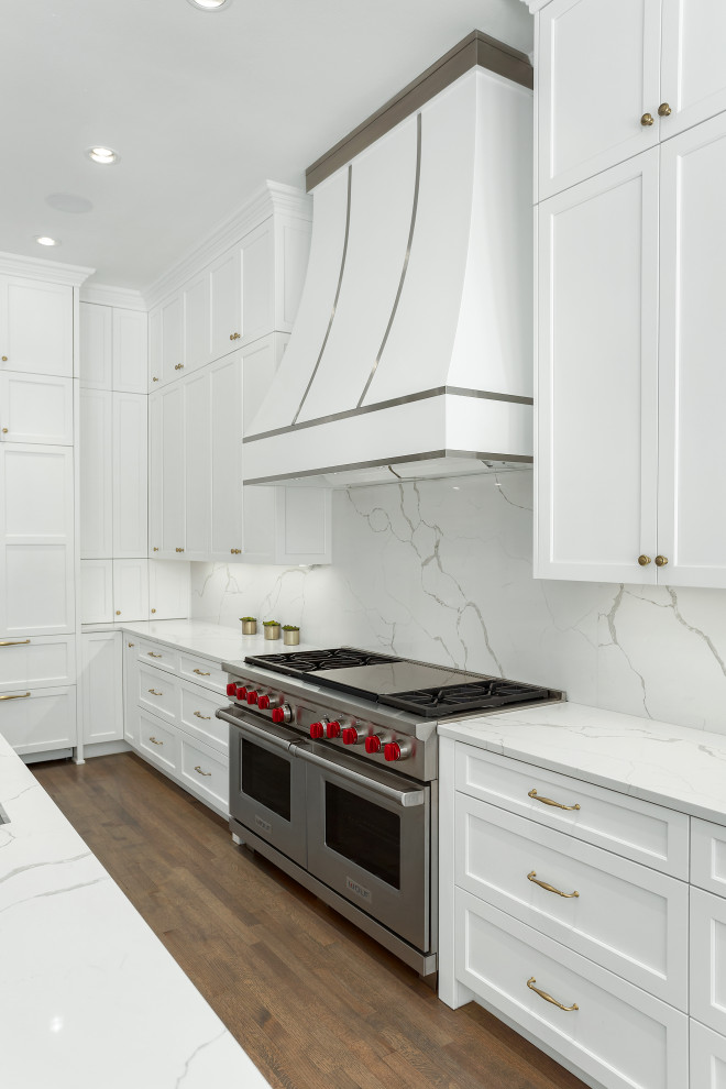 Exempel på ett stort klassiskt vit vitt kök, med en undermonterad diskho, luckor med infälld panel, vita skåp, bänkskiva i kvarts, vitt stänkskydd, rostfria vitvaror, mörkt trägolv, en köksö och brunt golv