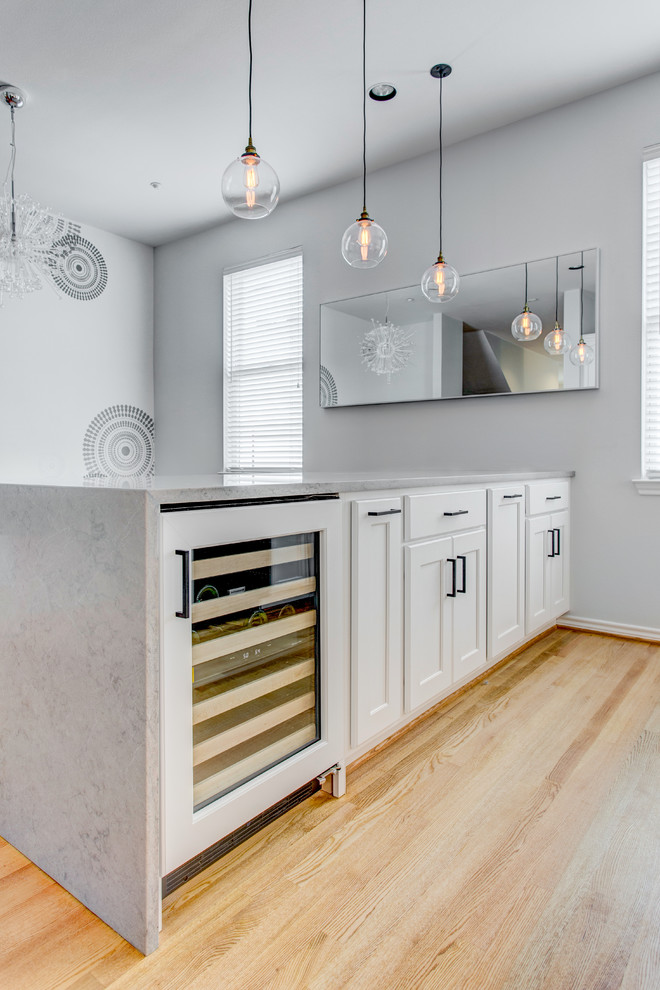 Idéer för att renovera ett mellanstort vintage grå grått kök, med en undermonterad diskho, luckor med infälld panel, vita skåp, bänkskiva i kvarts, vitt stänkskydd, stänkskydd i glaskakel, svarta vitvaror, ljust trägolv och en halv köksö