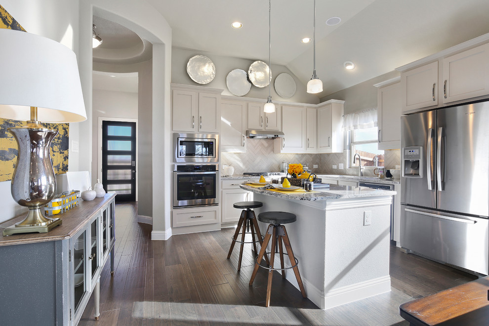 Modern inredning av ett stort kök, med en dubbel diskho, luckor med infälld panel, vita skåp, marmorbänkskiva, vitt stänkskydd, stänkskydd i keramik, rostfria vitvaror, mörkt trägolv, en köksö och brunt golv