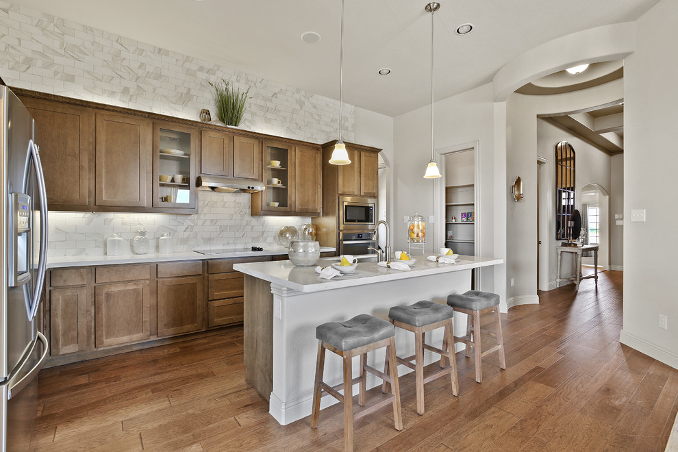 Inspiration for a mid-sized contemporary l-shaped medium tone wood floor and brown floor eat-in kitchen remodel in Dallas with a double-bowl sink, shaker cabinets, medium tone wood cabinets, solid surface countertops, beige backsplash, subway tile backsplash, stainless steel appliances, an island and beige countertops