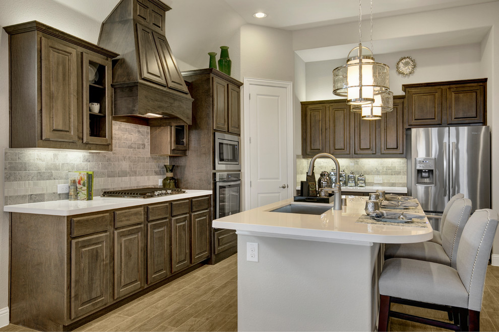 Inspiration for a large transitional l-shaped light wood floor and beige floor eat-in kitchen remodel in Dallas with a double-bowl sink, raised-panel cabinets, dark wood cabinets, solid surface countertops, beige backsplash, stone tile backsplash, stainless steel appliances and an island