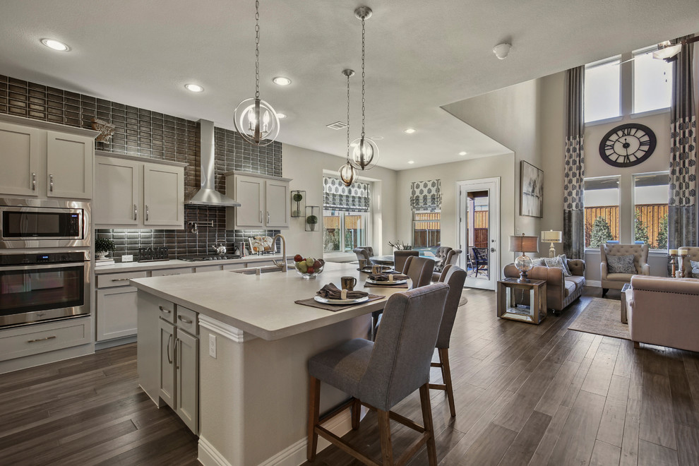 Eat-in kitchen - large rustic l-shaped dark wood floor and brown floor eat-in kitchen idea in Dallas with a double-bowl sink, recessed-panel cabinets, gray cabinets, solid surface countertops, gray backsplash, subway tile backsplash, stainless steel appliances and an island