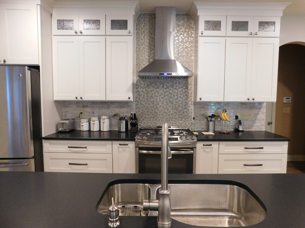 Foto di una piccola cucina classica con lavello a doppia vasca, ante in stile shaker, ante bianche, top in granito, paraspruzzi grigio, elettrodomestici in acciaio inossidabile, parquet chiaro e pavimento marrone