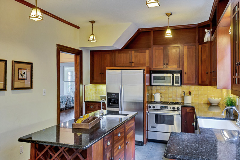 Foto på ett amerikanskt kök, med en rustik diskho, skåp i shakerstil, skåp i mellenmörkt trä, laminatbänkskiva, gult stänkskydd, stänkskydd i keramik, rostfria vitvaror, klinkergolv i keramik och en köksö