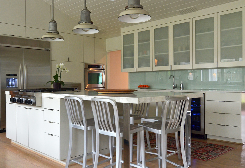 ダラスにあるトランジショナルスタイルのおしゃれなキッチン (ガラス扉のキャビネット、白いキャビネット、ガラス板のキッチンパネル、シルバーの調理設備、淡色無垢フローリング) の写真