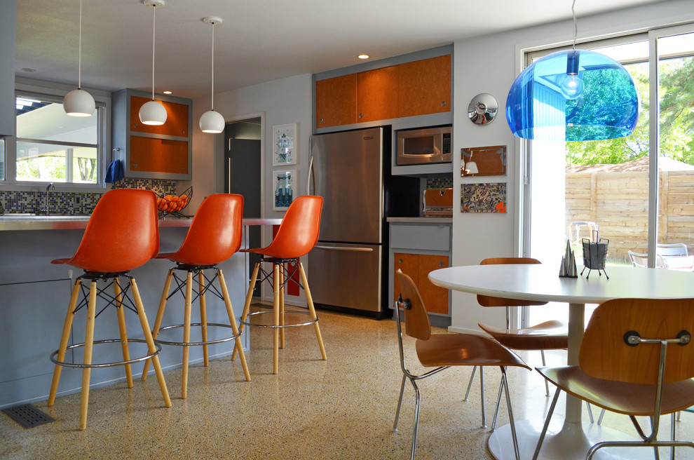 Eat-in kitchen - mid-century modern eat-in kitchen idea in Dallas with stainless steel appliances, flat-panel cabinets, multicolored backsplash and mosaic tile backsplash
