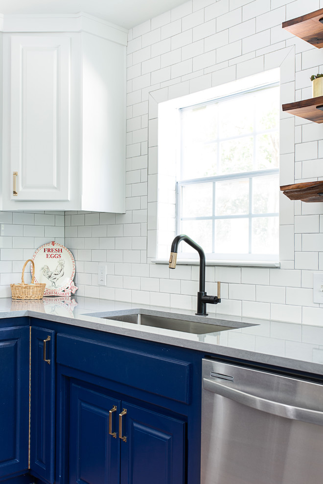 Inredning av ett lantligt mellanstort grå grått kök, med en undermonterad diskho, luckor med upphöjd panel, blå skåp, bänkskiva i kvarts, vitt stänkskydd, stänkskydd i keramik, rostfria vitvaror och en köksö