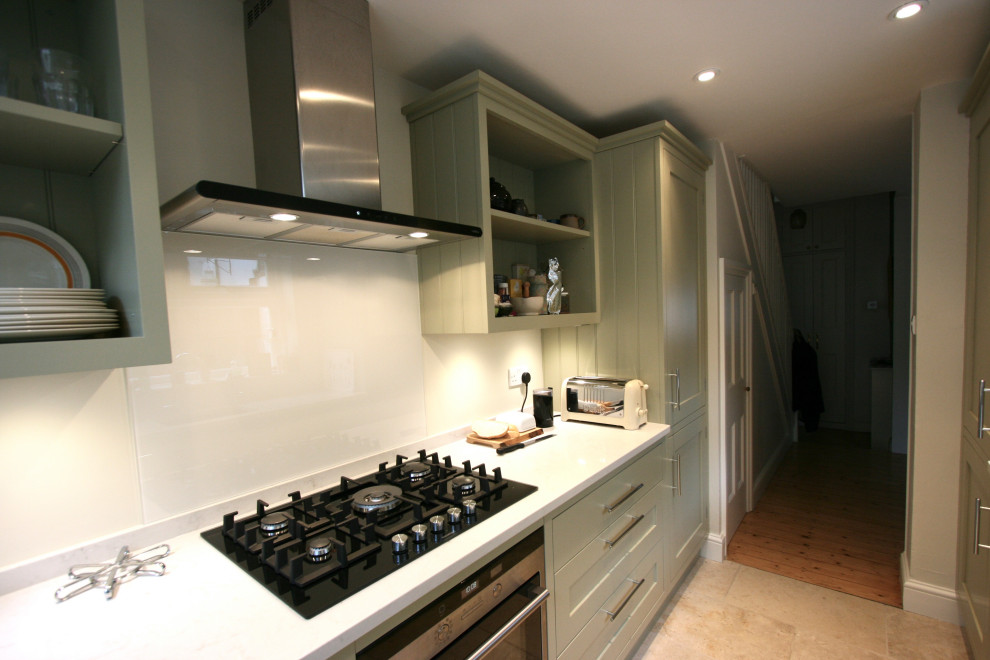 Photo of a small traditional kitchen/diner in London with a submerged sink, shaker cabinets, green cabinets, composite countertops, grey splashback, black appliances, limestone flooring, no island, beige floors and grey worktops.