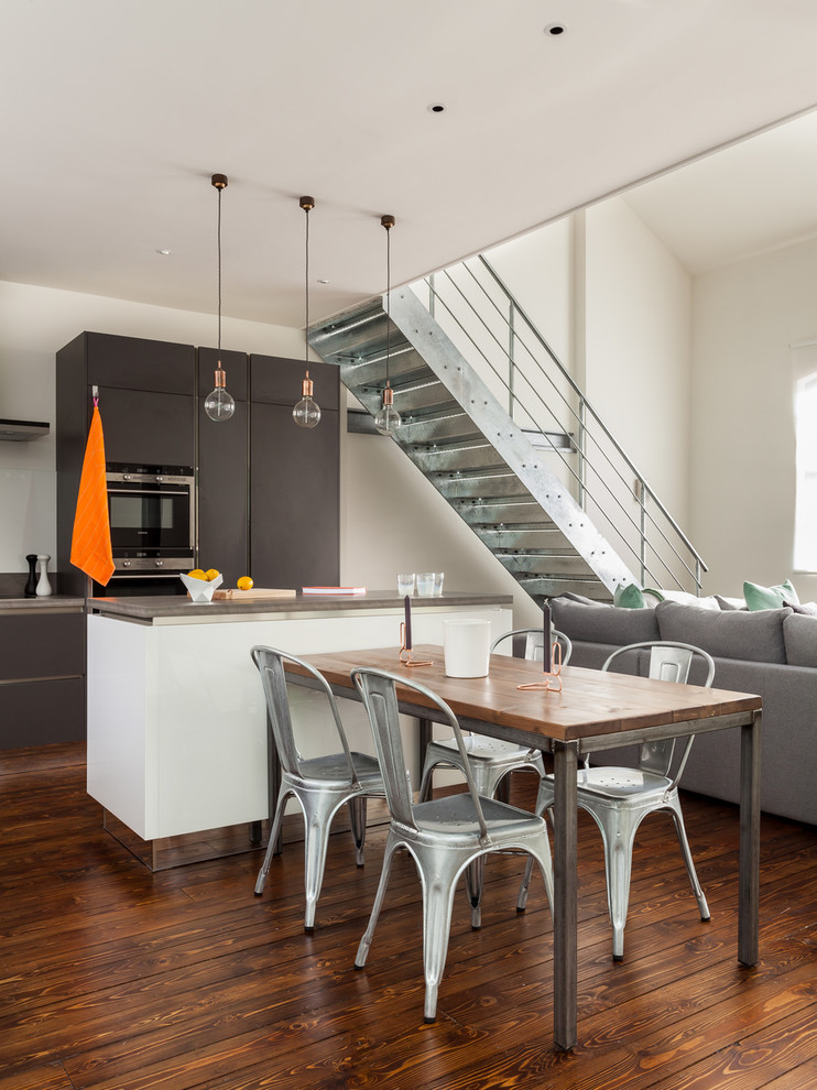 Идея дизайна: угловая кухня-гостиная в стиле лофт с серыми фасадами, техникой из нержавеющей стали и островом