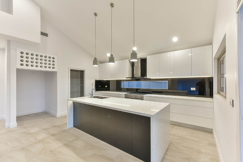 Design ideas for a large galley kitchen pantry in Sydney with a built-in sink, engineered stone countertops, black splashback, glass sheet splashback, stainless steel appliances, porcelain flooring, an island and multi-coloured floors.