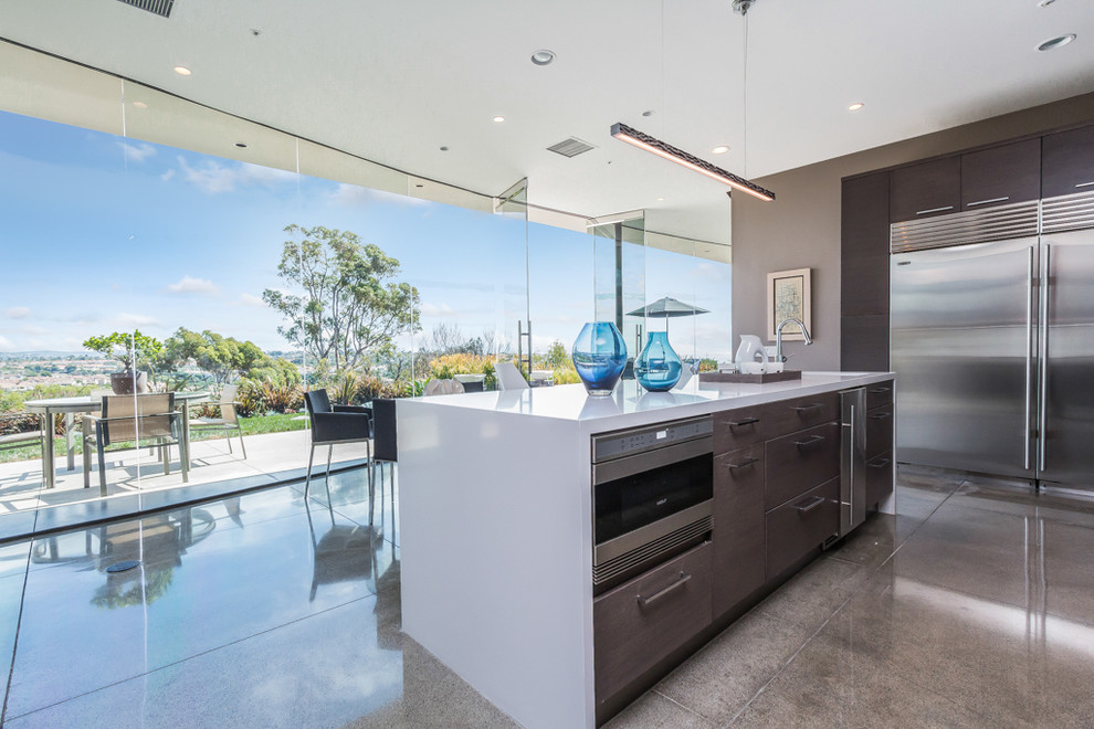 Open concept kitchen - mid-sized contemporary l-shaped concrete floor open concept kitchen idea in Orange County with an undermount sink, flat-panel cabinets, gray cabinets, quartz countertops, white backsplash, stainless steel appliances and an island