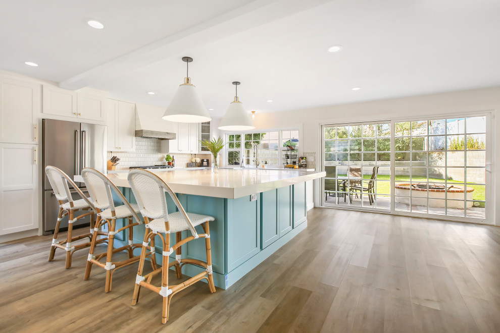 Example of a huge farmhouse u-shaped medium tone wood floor and brown floor eat-in kitchen design in Orange County with a farmhouse sink, shaker cabinets, white cabinets, quartzite countertops, white backsplash, cement tile backsplash, stainless steel appliances, an island and white countertops
