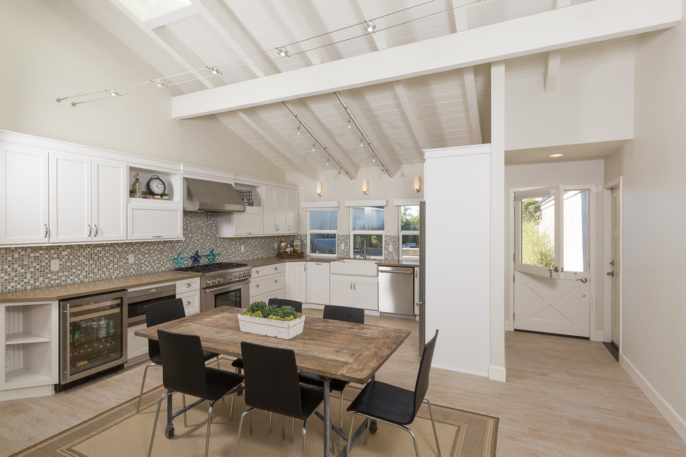 Eat-in kitchen - transitional u-shaped eat-in kitchen idea in Orange County with a farmhouse sink, shaker cabinets, white cabinets, multicolored backsplash, mosaic tile backsplash and stainless steel appliances