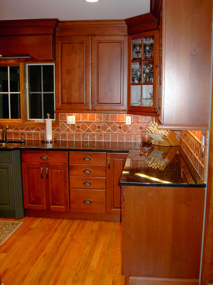 Example of a mid-sized arts and crafts u-shaped light wood floor and brown floor eat-in kitchen design in New York with raised-panel cabinets, dark wood cabinets, orange backsplash, terra-cotta backsplash, granite countertops and multicolored countertops