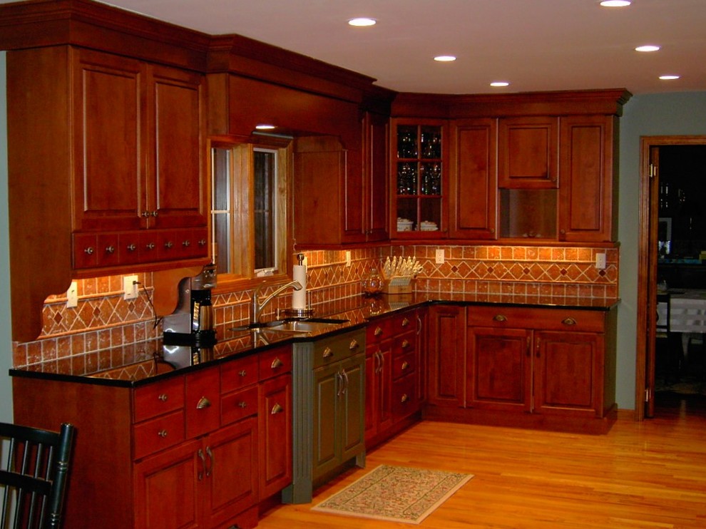 Esempio di una cucina american style di medie dimensioni con lavello a doppia vasca, ante con bugna sagomata, paraspruzzi arancione, paraspruzzi con piastrelle in terracotta, pavimento marrone, ante rosse, top in granito, pavimento in legno massello medio e top nero