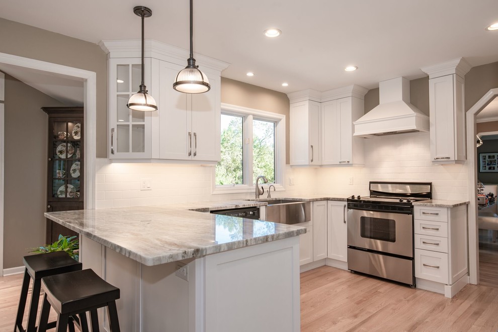 Large transitional u-shaped light wood floor and beige floor eat-in kitchen photo in New York with a farmhouse sink, shaker cabinets, white cabinets, marble countertops, white backsplash, subway tile backsplash, stainless steel appliances, a peninsula and gray countertops
