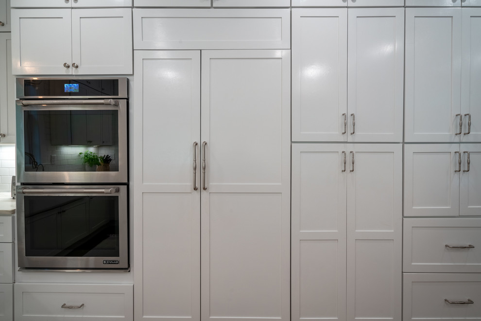 Foto på ett stort lantligt vit kök, med en rustik diskho, skåp i shakerstil, vita skåp, marmorbänkskiva, vitt stänkskydd, stänkskydd i tunnelbanekakel, rostfria vitvaror och mellanmörkt trägolv