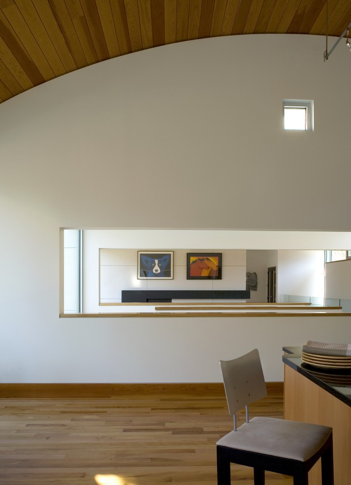 Cette image montre une cuisine américaine parallèle minimaliste en bois clair avec un placard à porte plane, un plan de travail en granite, parquet clair et îlot.