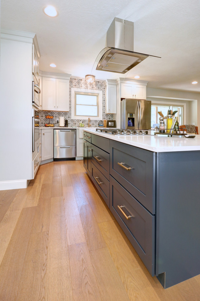 Photo of a classic l-shaped open plan kitchen in Other with a belfast sink, shaker cabinets, grey cabinets, marble worktops, grey splashback, mosaic tiled splashback, stainless steel appliances, light hardwood flooring, an island, yellow floors and white worktops.