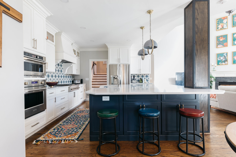Example of a transitional l-shaped dark wood floor and brown floor open concept kitchen design in Nashville with shaker cabinets, white cabinets, multicolored backsplash, stainless steel appliances, an island and white countertops