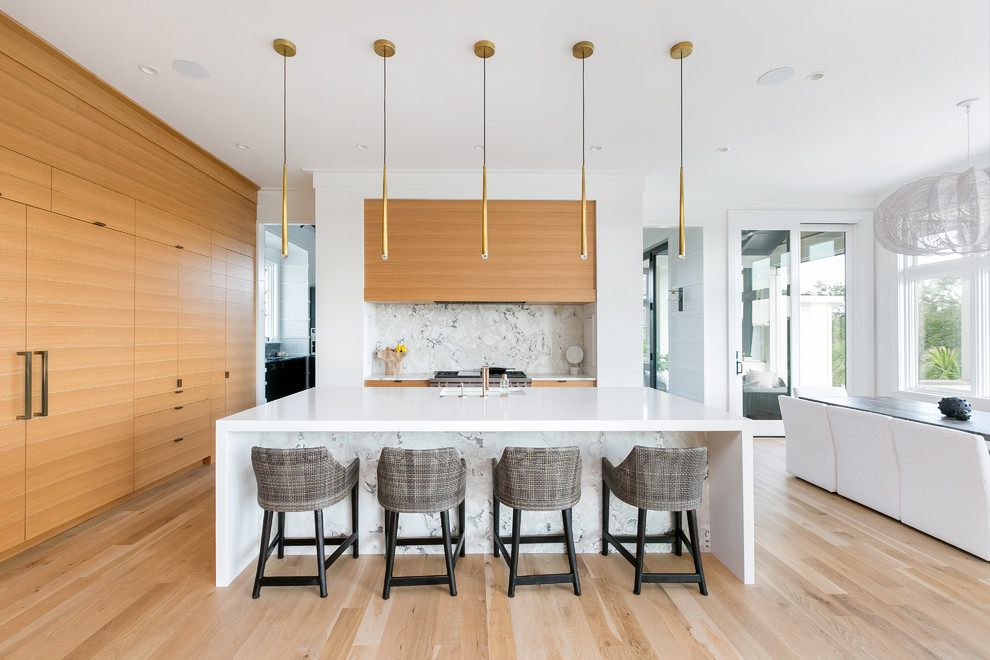 This is an example of a contemporary kitchen/diner in Charleston with a submerged sink, flat-panel cabinets, medium wood cabinets, integrated appliances, light hardwood flooring, an island, beige floors and white worktops.