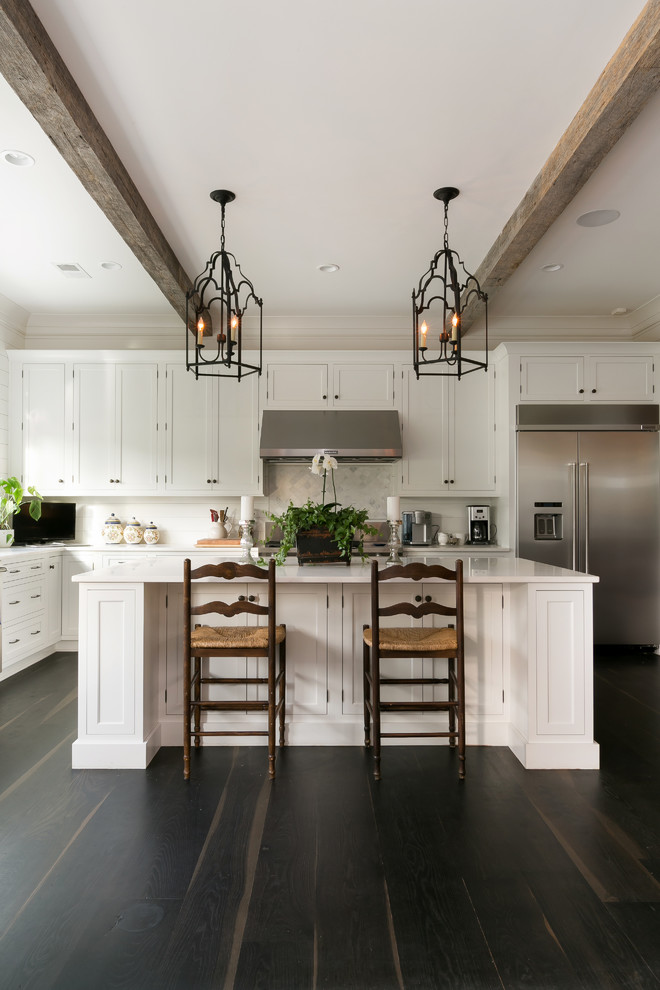 Inspiration for a traditional l-shaped kitchen in Charleston with shaker cabinets, white cabinets, white splashback, stainless steel appliances, dark hardwood flooring and an island.